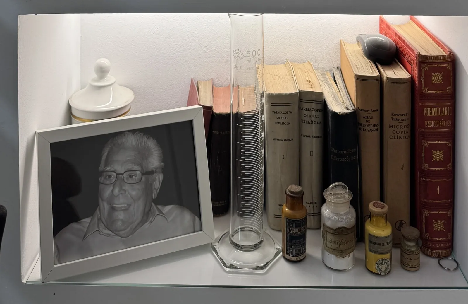 Retrato del fundador Alfonso Lorite junto a los libros de formulario y una probeta